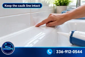 Hand smoothing a fresh white caulk line where a refinished bathtub meets the tiled wall